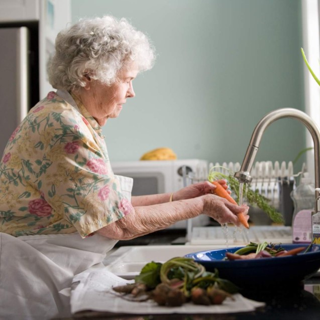 Lady cleaning vegetables at the sink