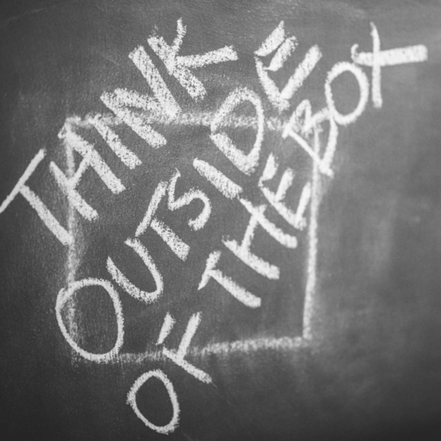 Text on a blackboard, 'Think outside of the box'.